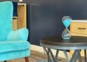 Thumbnail 9 of 12 - a blue chair and a round table with an hourglass on it at 2300 West Apartments, Nevada, 89502