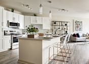 Thumbnail 2 of 39 - A modern kitchen with a white color scheme and a large island.