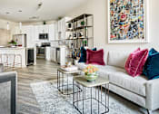 Thumbnail 1 of 39 - A modern living room with a grey couch and a large abstract painting on the wall.