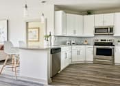 Thumbnail 5 of 39 - A modern kitchen with white cabinets and stainless steel appliances.