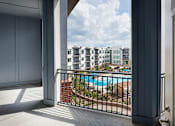 Thumbnail 12 of 39 - A balcony with a pool and buildings in the background.
