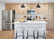 Thumbnail 1 of 19 - A modern kitchen with a white island and stainless steel appliances. at Lucie at Tradition Apartments, Port St. Lucie, Florida