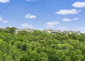 Thumbnail 12 of 23 - a row of apartments sitting on top of a lush green forest