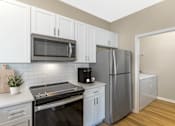 Thumbnail 4 of 29 - Kitchen and attached laundry room with stainless steel appliances and modern finishes