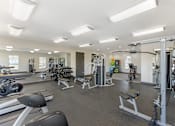 Thumbnail 16 of 29 - A well-equipped gym with various exercise machines and weights.