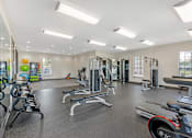 Thumbnail 17 of 29 - A spacious gym with a variety of equipment including treadmills, weights, and exercise machines.
