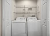 Thumbnail 14 of 26 - Two white washing machines in a small laundry room.