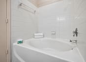 Thumbnail 12 of 26 - A white bathroom with a white tub and a white towel.