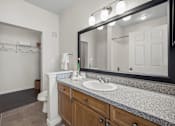 Thumbnail 11 of 26 - A bathroom with a sink, mirror, and toilet.