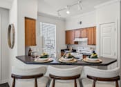 Thumbnail 5 of 26 - A kitchen with a table set for two with a white chair on either side.
