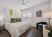 Thumbnail 9 of 26 - A bedroom with a bed, chair, and artwork on the wall.