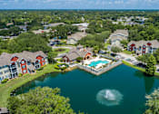 Thumbnail 23 of 38 - A bird's eye view of a residential area with houses surrounding a lake.