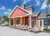 Thumbnail 16 of 38 - A red brick house with a porch and lounge chairs in front.