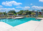 Thumbnail 13 of 38 - A swimming pool surrounded by a concrete deck and a residential area in the background.