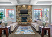 Thumbnail 25 of 38 - A living room with a stone fireplace and a flat screen TV mounted above it.