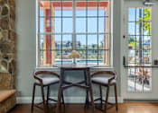 Thumbnail 26 of 38 - A dining room with a table and chairs in front of a large window.