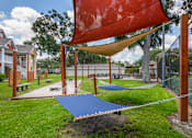 Thumbnail 32 of 38 - A playground with a red shade sail and a blue slide.