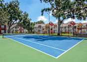 Thumbnail 28 of 38 - A tennis court is surrounded by apartment buildings.