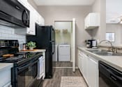 Thumbnail 9 of 38 - A black stove top oven sits next to a black microwave in a kitchen.