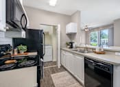 Thumbnail 10 of 38 - A modern kitchen with a black refrigerator and stove top oven.