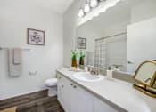 Thumbnail 2 of 38 - A bathroom with a toilet, sink, mirror, and a plant on the counter.
