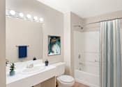 Thumbnail 6 of 35 - A bathroom with a white sink, vanity, toilet, and bathtub/shower