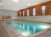 Thumbnail 17 of 35 - A large indoor swimming pool with a brick wall and windows.