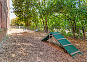 Thumbnail 27 of 35 - A playground with a green slide and a brown wall.