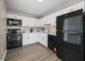 Thumbnail 9 of 30 - A black fridge in a kitchen with white cabinets.