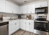 Thumbnail 3 of 30 - A kitchen with white cabinets and stainless steel appliances.