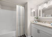 Thumbnail 5 of 30 - A bathroom with a white tub, sink, and striped shower curtain.