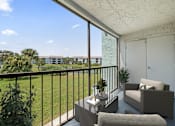 Thumbnail 11 of 30 - A balcony with a couch, chair, and table with a view of apartment buildings.
