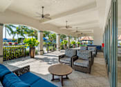 Thumbnail 7 of 32 - An outdoor lounge area that is covered with a ceiling and paddle fans