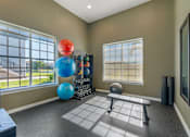 Thumbnail 24 of 32 - A room with a large window, a bench, and exercise equipment.