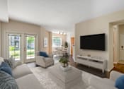 Thumbnail 12 of 32 - A living room with a white couch, a white coffee table, and a black television.