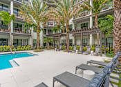 Thumbnail 17 of 49 - A pool surrounded by palm trees and lounge chairs.
