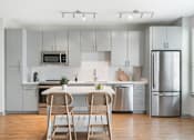 Thumbnail 13 of 49 - A modern kitchen with a white color scheme and stainless steel appliances.