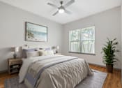 Thumbnail 9 of 49 - A bedroom with a large bed, a ceiling fan, and a potted plant.