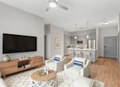 Thumbnail 1 of 49 - A living room with a television, white chairs, and a wooden coffee table.