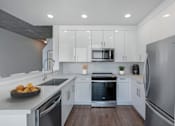Thumbnail 7 of 48 - A modern kitchen with stainless steel appliances and white cabinets.
