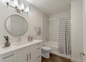 Thumbnail 4 of 48 - A white bathroom with a round mirror and a white toilet.