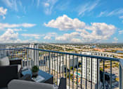 Thumbnail 8 of 48 - A balcony with a table and chairs overlooking a cityscape.