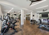Thumbnail 16 of 49 - A gym with a variety of equipment including treadmills, stationary bikes, and weight machines.
