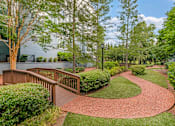 Thumbnail 20 of 49 - A pathway with a wooden railing on the left side and a grassy area on the right.