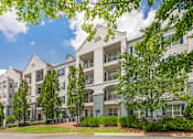 Thumbnail 42 of 49 - A large white apartment building with balconies and trees in front.