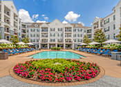 Thumbnail 15 of 49 - A large pool surrounded by a flower bed in front of apartment buildings.
