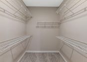 Thumbnail 9 of 49 - Empty walk-in closet with shelves and a carpeted floor.