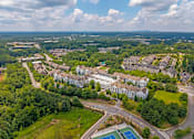Thumbnail 47 of 49 - A bird's eye view of a residential area with apartment buildings, roads, and a tennis court.