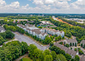 Thumbnail 48 of 49 - A large white building is surrounded by trees and a road.