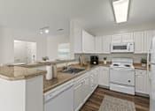 Thumbnail 1 of 34 - A white kitchen with a stove, microwave, and refrigerator.